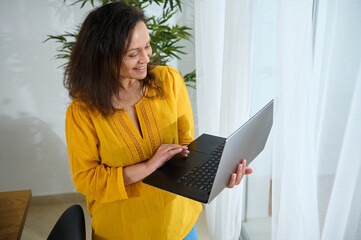 Smiling Professional Woman Working Remotely on Laptop in Bright Home Office