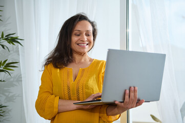 Smiling Woman Working Remotely on Laptop in Bright, Modern Home Office