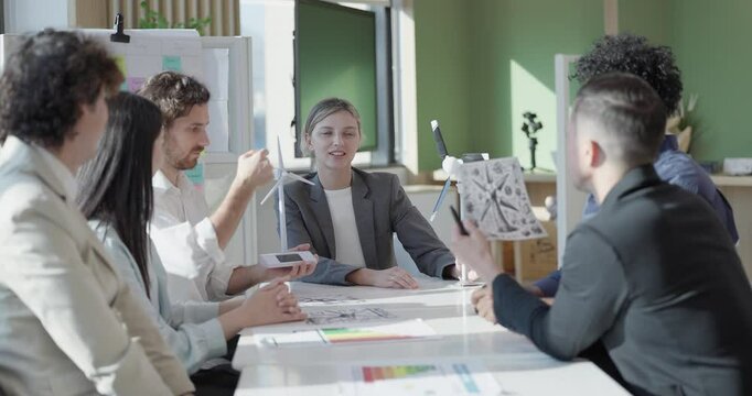 A diverse startup team develop, collaborates on a powerful, lightweight, portable wind turbine prototype, aligning with potential user demand and renewable energy needs to secure investor funding.
