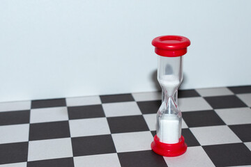 small red hourglass close-up on a chess board