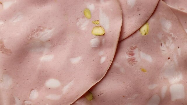  rotating close-up view of Italian mortadella with pistachios, showcasing its marbled texture and gourmet delicacy, concept of traditional Italian charcuterie, fine dining, and premium deli meats