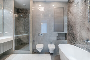 Bathroom with modern design, marble tile finish. Shower with a tropical watering can, behind a...