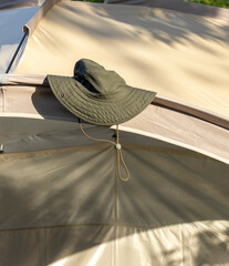 dark green panama hat lies on beige tent in sun rays
