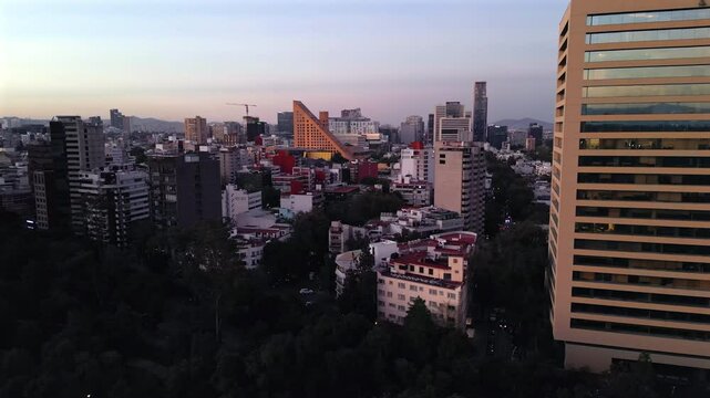Flying over upscale Polanco at dusk with towers and modern architecture.