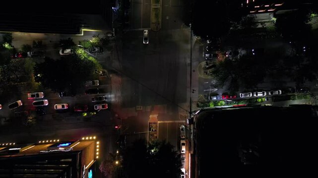 Top shot of intersection at night with near accident when motorcycle runs a red light. Mexico City.