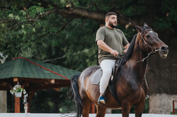 Fototapeta premium Man riding a horse outdoors in a park, engaging in a recreational horseback riding activity on a sunny day.