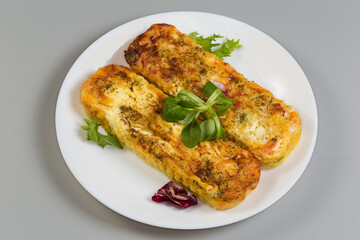 Rectangular vegetable casseroles with cheese on dish on gray background