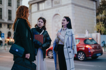 Obraz premium Three businesswomen engage in a conversation outdoors on a city street. The scene captures their collaborative and engaging interaction in a bustling, urban setting.