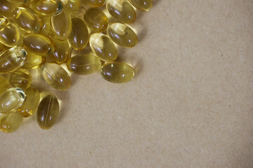 Liquid gold gel capsule of vitamin D displayed on a white surface.