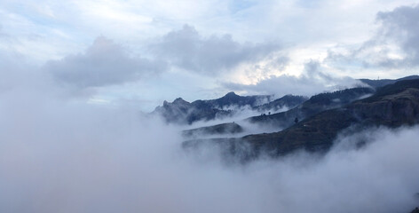 Fog rolling over majestic mountain peaks at dusk