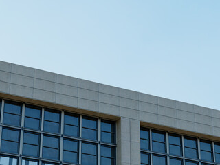 Fototapeta premium Modern high-rise building corner with a clear glass facade and blue sky.