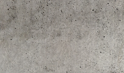 Close-up of a rough, porous concrete wall surface with small holes, imperfections, and a textured...