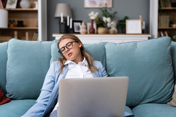 Overworked tired businesswoman sleeping on sofa in home office. Young exhausted girl working from...
