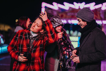 Friends interacting and enjoying themselves outside during a winter evening with festive lights.