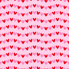 Seamless pattern with bright pink and red hearts on a light pink background. Vector Valentine's Day background.	
