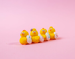 Row of decorative candy Easter chickens on light pink background