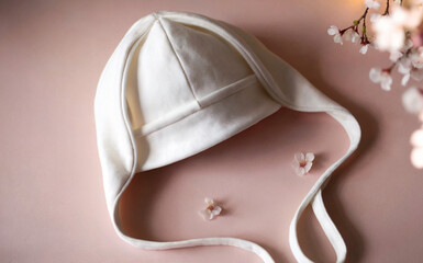 Mockup of a baby cotton hat with ears on a pink background with small flowers. Ideal for showcasing original prints or brand logos.