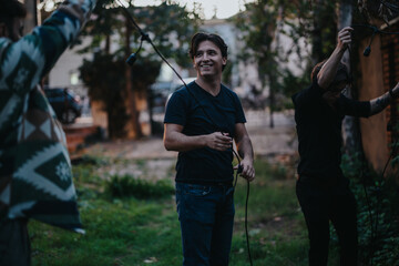 A group of friends assembling audio or lighting gear in an outdoor setting, sharing laughter and...