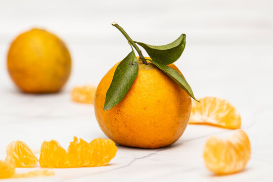 Landscape photo with white background and ripe oranges and its slices around it.