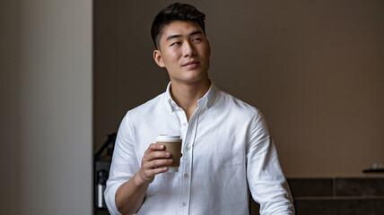 Young Asian Man Standing with Coffee in a Relaxed and Confident Mood