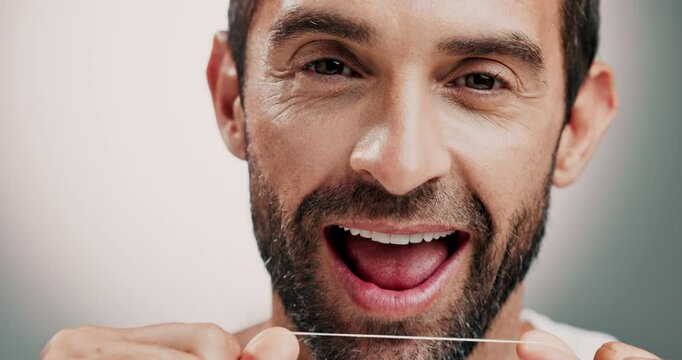 Dental health, face and man with floss in studio for cleaning, hygiene or morning mouth routine. Oral care, grooming and portrait of person with teeth string to prevent gum disease by gray background