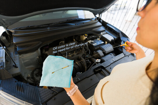 Point of view of a woman wearing AR glasses examining oil level in car engine, displaying real-time diagnostic data on transparent display