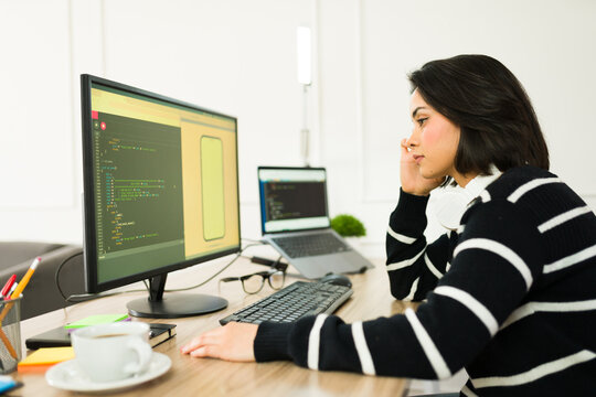 Female programmer typing code on laptop, working from home office with modern workspace background