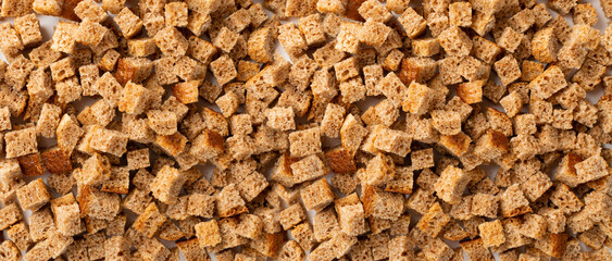 Homemade rye bread croutons texture background top view. Crispy bread cubes pattern