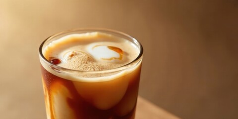 A Refreshing Iced Coffee Beverage with Creamy Foam and a Subtle Caramel Drizzle in a Clear Glass