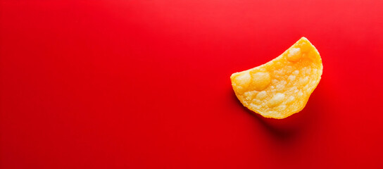 Naklejka premium Single potato chip on a red background