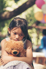 Vertical Sad girl hug teddy bear sit sadness alone in green park. Vertical Lonely girl feeling sad...