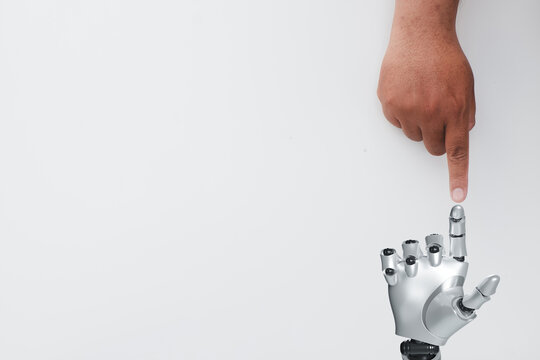 Close-up of a human hand pointing at a robotic hand over white background with copyspace concept for  futuristic robotics innovation,human evolution, AI technology,human-robot collaboration.