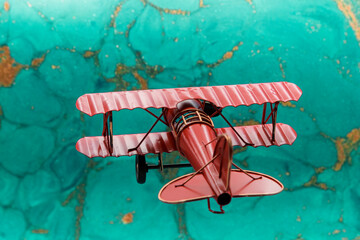 Avión biplano clásico pintado de rojo de hélice, con fondo azul abstracto
