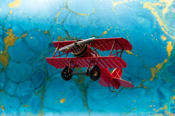 Avión biplano clásico pintado de rojo de hélice, con fondo azul abstracto