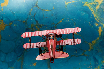 Avión biplano clásico pintado de rojo de hélice, con fondo azul abstracto