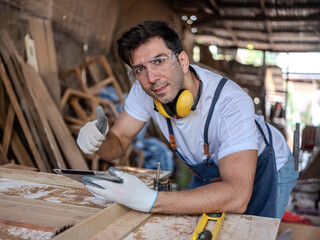 Professional Carpenter use tablet  working to making woodcraft furniture in wood workshop look professional high skill making furniture. masterpieces .