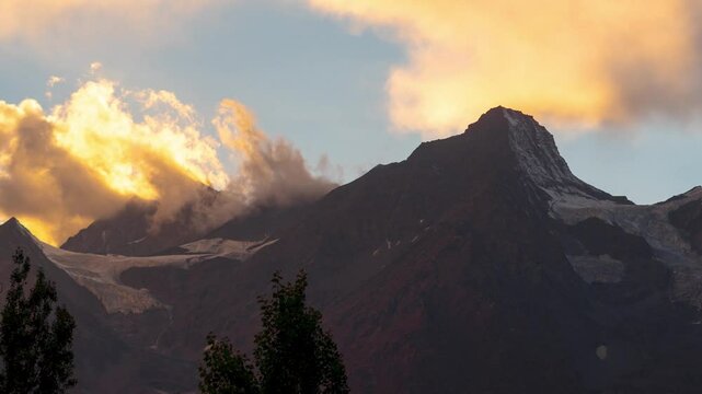 4K timelapse shot of orange clouds moving above mountains during sunset at Keylong, Lahaul, India. Nature background. Mountain and clouds background. 