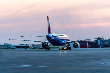 Airplane ready to fly at the airport with the backdrop of a blue and crimson sunset scenic sky with...
