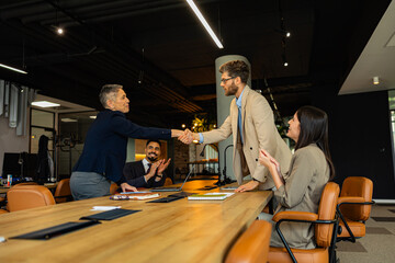 Obraz premium Happy male and female entrepreneurs came to an agreement during a meeting with their colleagues in the modern office.