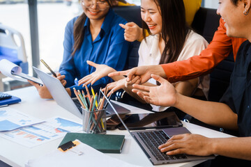 Five young Asian professionals collaborate at startup business meeting, working at desk with...