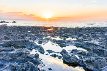 Fototapeta premium beautiful golden sunset or sunrise on a seashore bank with blue sea water and yellow sunnny evening cloudy sky