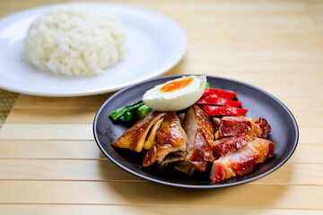 Roast Duck and Char Siu with Rice and salted boiled egg served in plate isolated on table closeup side view of Hong Kong food