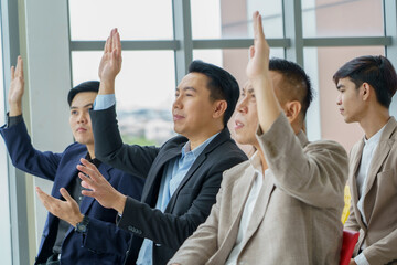Obraz premium group of asian business people sitting in meeting at seminar or listener raising hand to ask question. audience hand up