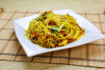 Xingzhou Fried Rice Noodles include vermicelli stir fried with shrimp, vegetables, and curry powder served in plate isolated on table closeup side view of Hong Kong food
