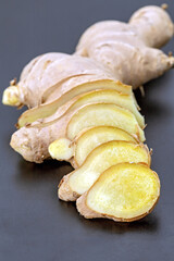 Fresh ginger sliced ​​into pieces placed on a black plate ready for cooking.