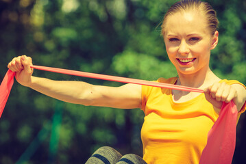 Girl doing exercise outdoor, using resistance fit band.