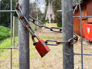 gate with mesh closed on red old padlock with chain