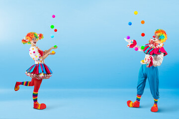 Funny jugglers clowns juggling balls in the circus, entertainers as Joker in a suit and wig, with...