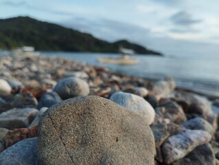 The photo captures a smooth, weathered stone resting on a rocky beach.