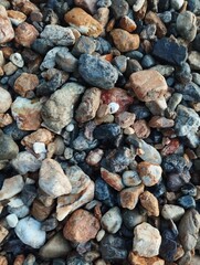 The photo captures a serene beach scene where a variety of smooth, weathered stones are scattered across the sandy shore. 